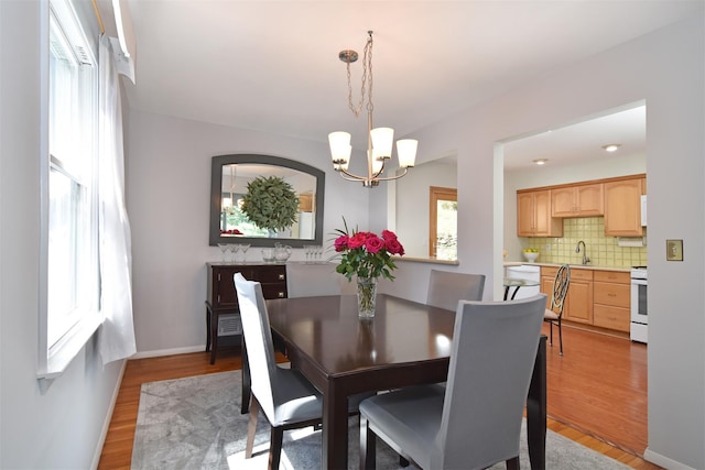 dining area with a notable chandelier, baseboards, and light wood-type flooring