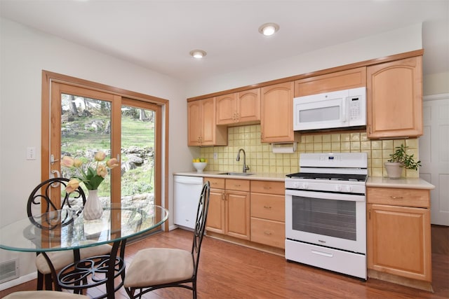 kitchen with light countertops, light brown cabinetry, wood finished floors, and white appliances