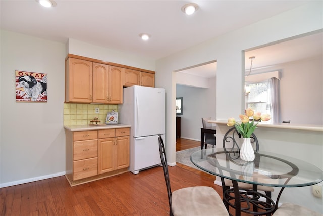 kitchen featuring wood finished floors, light countertops, freestanding refrigerator, and backsplash