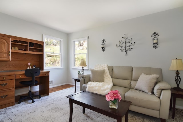 living room with visible vents, light wood-style flooring, and baseboards