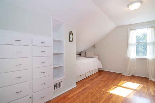 unfurnished bedroom featuring baseboards, visible vents, lofted ceiling, and light wood finished floors