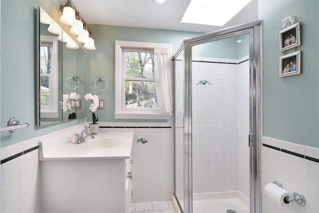 bathroom with tile walls, a stall shower, a wainscoted wall, and vanity