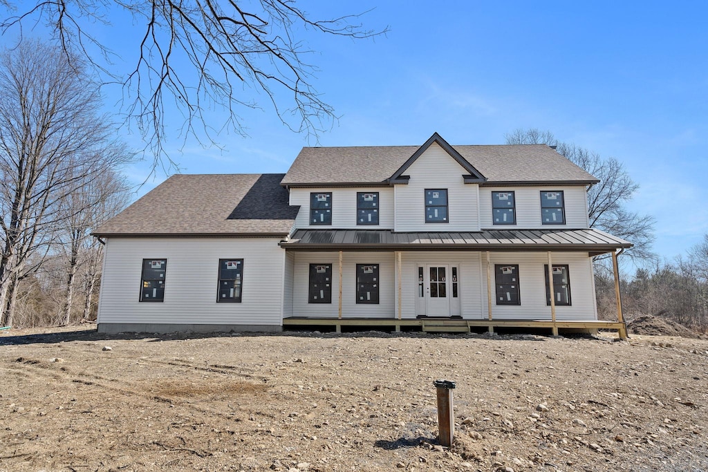 view of front of house with a porch, roof with shingles, a standing seam roof, and metal roof