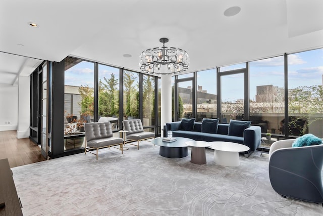 sunroom featuring a wealth of natural light, an inviting chandelier, wood finished floors, and expansive windows