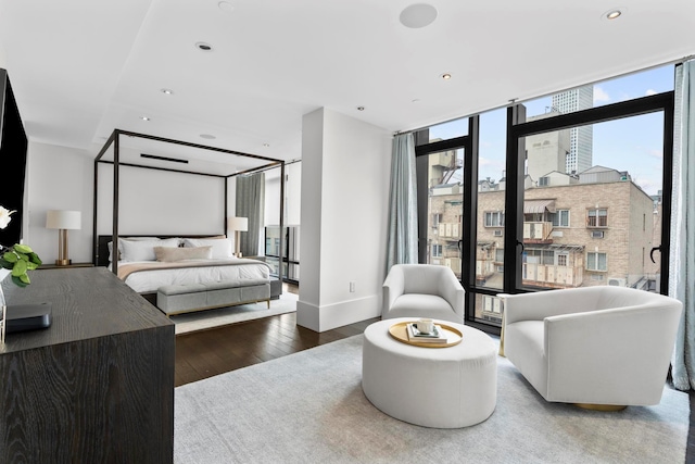 bedroom featuring recessed lighting, expansive windows, hardwood / wood-style flooring, and baseboards