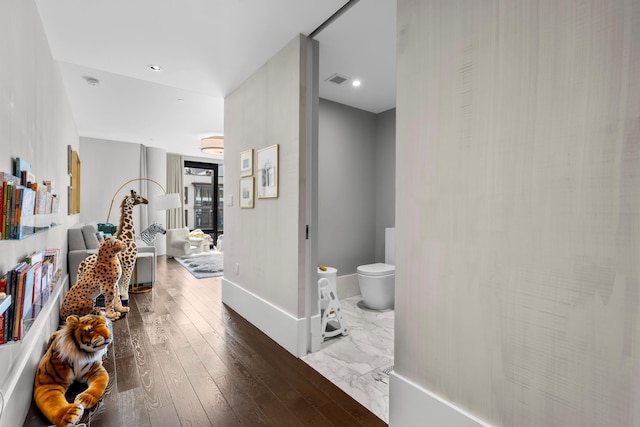 corridor featuring visible vents, baseboards, and wood finished floors