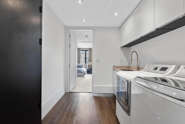 clothes washing area with baseboards, a sink, dark wood-style floors, independent washer and dryer, and cabinet space
