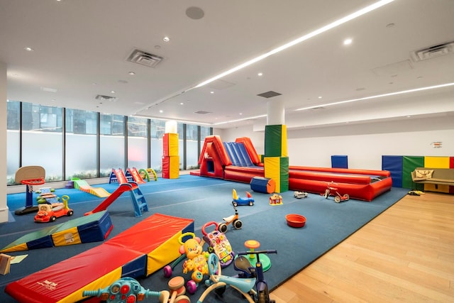 recreation room with visible vents, a wall of windows, and wood finished floors
