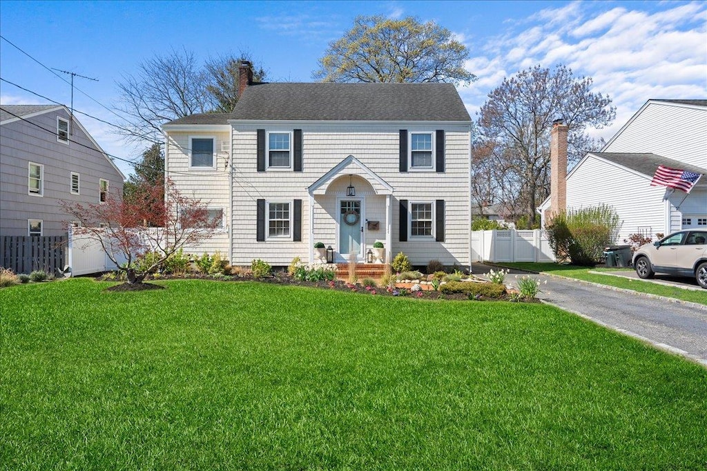 26 Seafield Ln, Bay Shore, NY 11706 - colonial home featuring fence, a chimney, a shingled roof, and a front yard