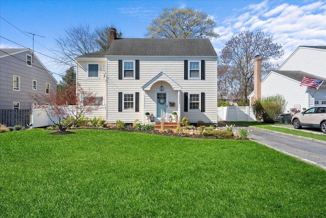 26 Seafield Ln, Bay Shore, NY 11706 - colonial home featuring fence, a chimney, a shingled roof, and a front yard