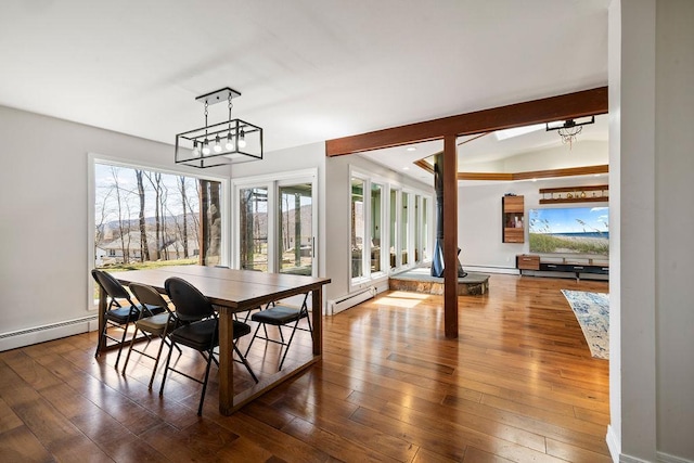 dining room with beam ceiling, baseboards, a baseboard heating unit, and hardwood / wood-style flooring