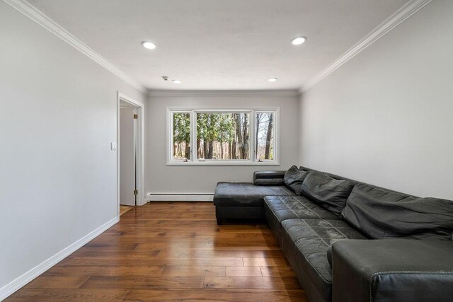 living room with baseboard heating, hardwood / wood-style floors, baseboards, and ornamental molding