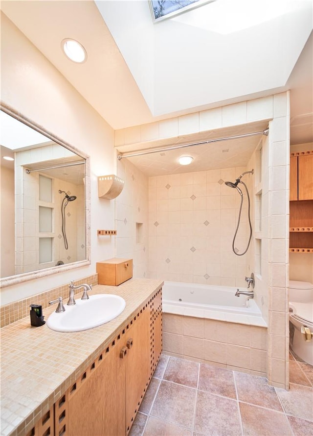 full bathroom with vanity, tile patterned flooring, toilet, a skylight, and tiled shower / bath combo