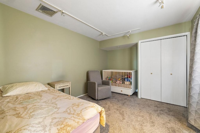carpeted bedroom featuring rail lighting, visible vents, a closet, and attic access