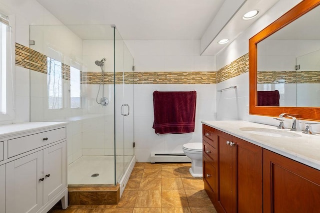 bathroom with toilet, tile walls, a shower stall, vanity, and a baseboard heating unit