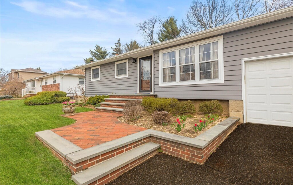 single story home featuring a garage and a front lawn