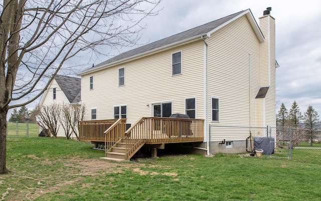 back of property featuring fence, a chimney, a lawn, and a deck