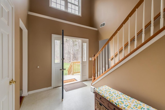 entrance foyer with visible vents, baseboards, light floors, a high ceiling, and stairs