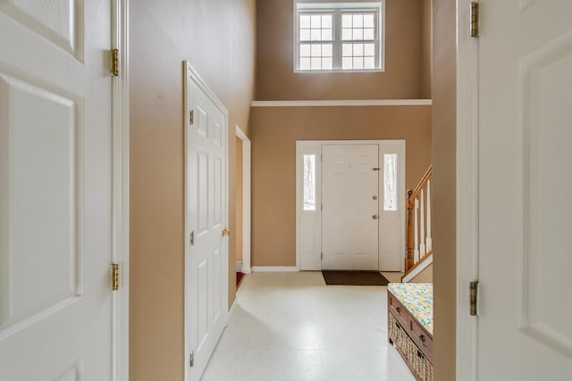 entryway featuring stairs, baseboards, and a towering ceiling