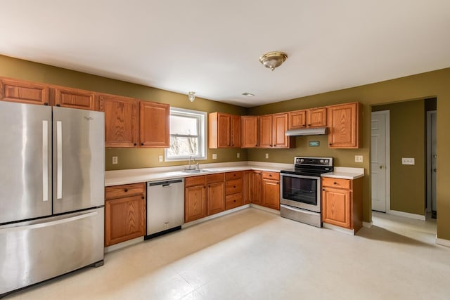 kitchen with a sink, light countertops, baseboards, under cabinet range hood, and stainless steel appliances