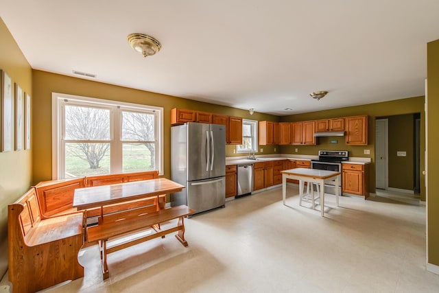 kitchen featuring a sink, light countertops, stainless steel appliances, under cabinet range hood, and visible vents