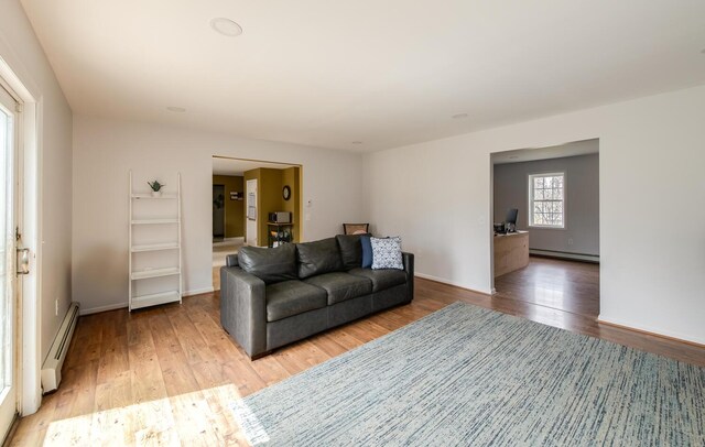living room featuring light wood-style floors, baseboards, a baseboard heating unit, and baseboard heating