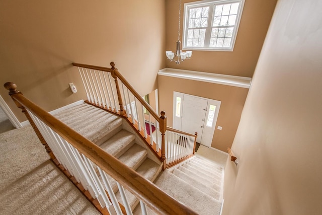 staircase with baseboards, carpet flooring, and a chandelier
