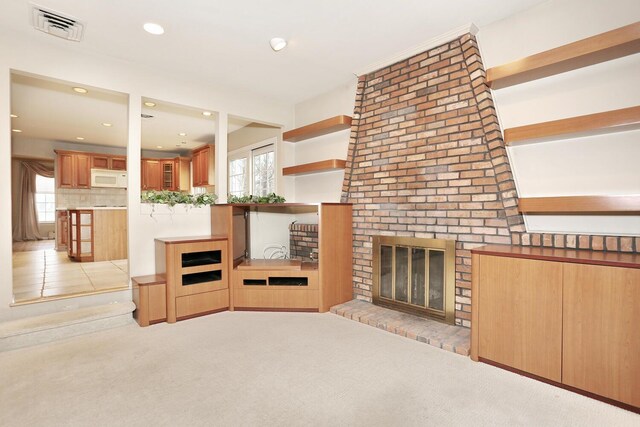 unfurnished living room with a healthy amount of sunlight, a brick fireplace, recessed lighting, and visible vents