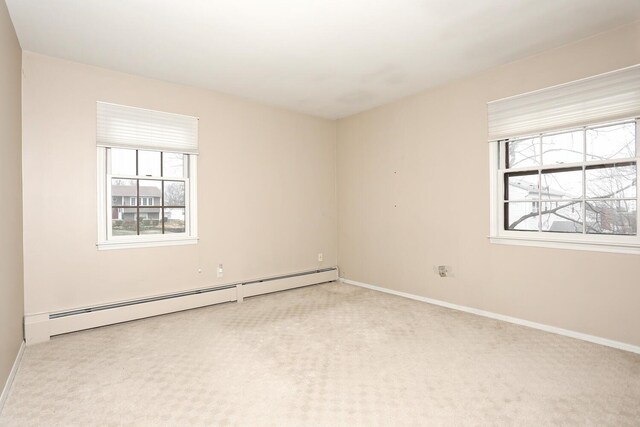 carpeted empty room featuring baseboards, baseboard heating, and a wealth of natural light