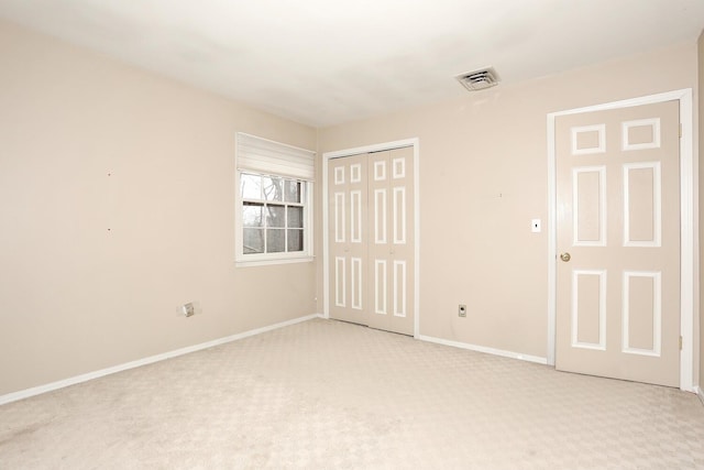 unfurnished bedroom with baseboards, light carpet, a closet, and visible vents