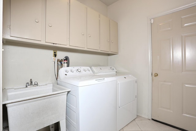 laundry area featuring cabinet space, light tile patterned floors, a sink, and washer and dryer