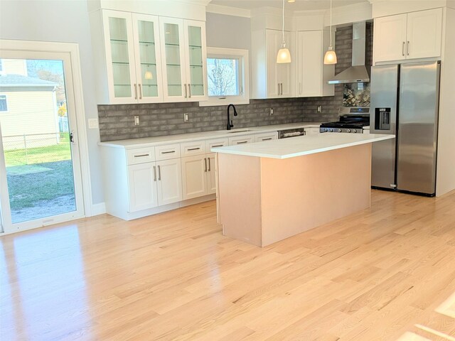1135 Logan Rd, Wantagh, NY 11793 - kitchen with appliances with stainless steel finishes, wall chimney range hood, light wood-style floors, a kitchen island, and ornamental molding