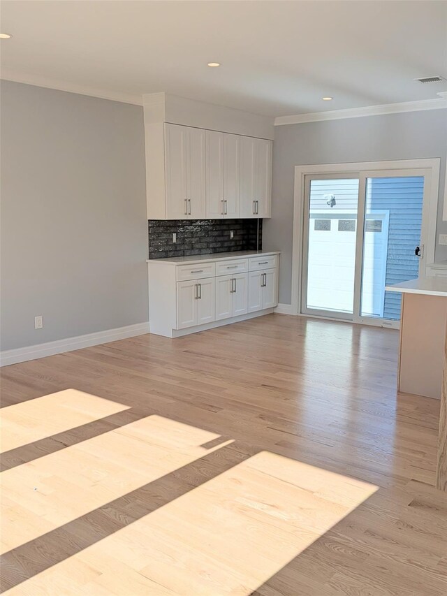 1135 Logan Rd, Wantagh, NY 11793 - kitchen featuring ornamental molding, white cabinetry, decorative backsplash, light wood-type flooring, and recessed lighting
