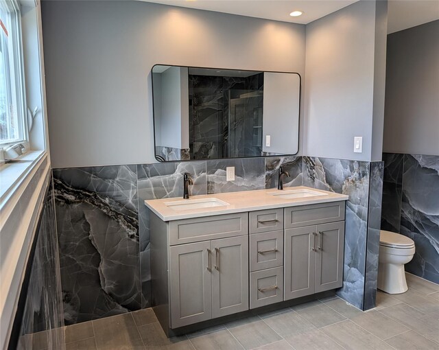 1135 Logan Rd, Wantagh, NY 11793 - full bath with tile walls, double vanity, toilet, a marble finish shower, and a wainscoted wall