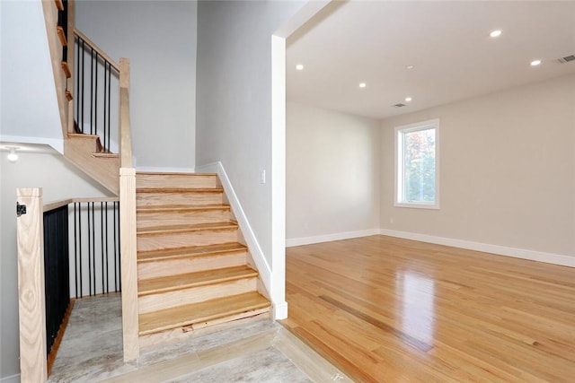 stairs with wood finished floors, baseboards, visible vents, and recessed lighting