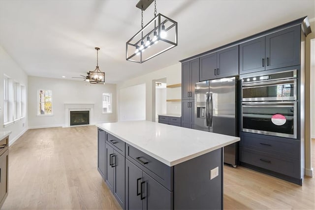 kitchen with light countertops, appliances with stainless steel finishes, light wood-style floors, and a fireplace