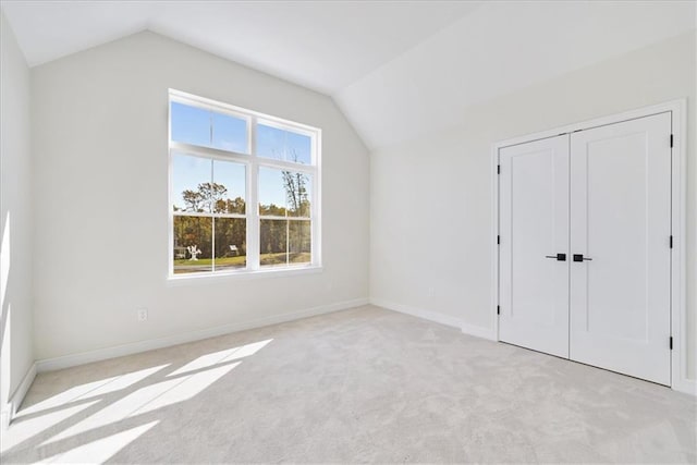 additional living space with baseboards, light carpet, and lofted ceiling