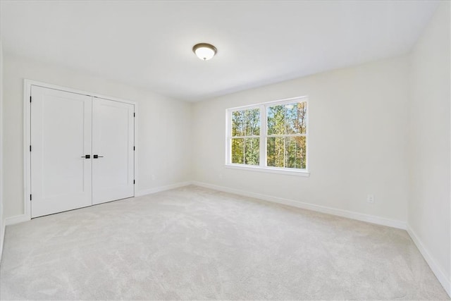 unfurnished room with baseboards and light carpet