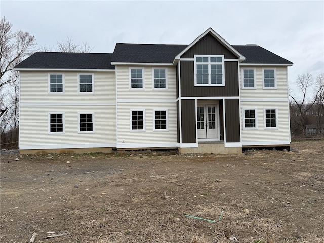 view of front facade with roof with shingles, french doors, and board and batten siding
