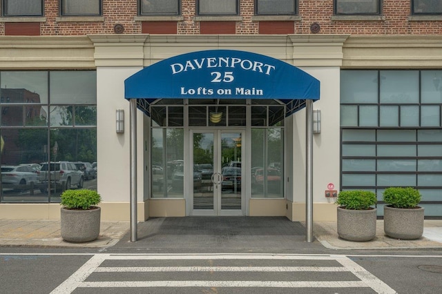 view of exterior entry featuring brick siding and french doors
