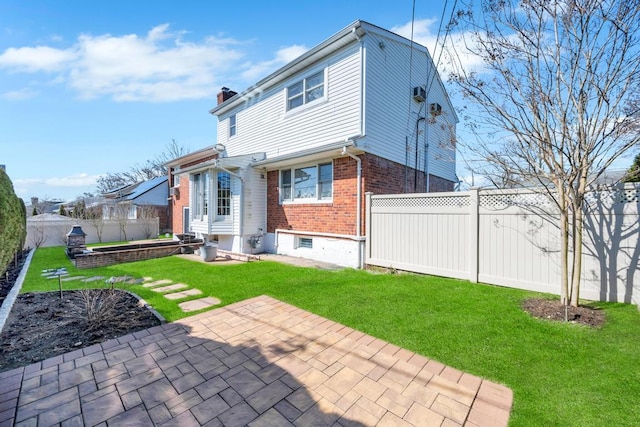 34 Duke Dr, Manhasset Hills, NY 11040 - back of house with a chimney, a fenced backyard, a patio, a lawn, and brick siding