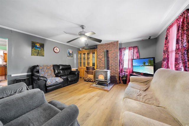 living area featuring a wood stove, ornamental molding, a ceiling fan, and wood finished floors
