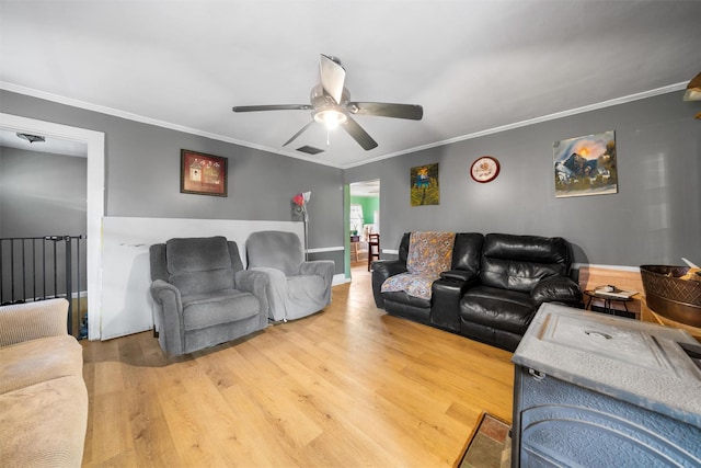living area with light wood finished floors, crown molding, and a ceiling fan