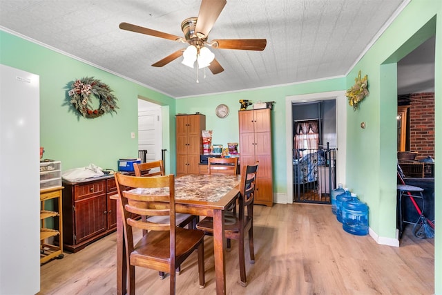 dining space featuring light wood-style floors, ceiling fan, crown molding, and baseboards