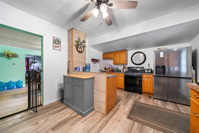 kitchen featuring stainless steel fridge with ice dispenser, light wood-type flooring, a ceiling fan, a peninsula, and black gas range