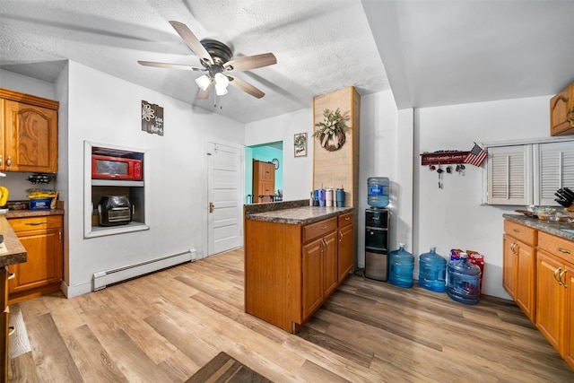 kitchen featuring brown cabinets, ceiling fan, light wood-type flooring, and a baseboard heating unit