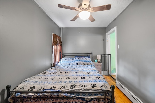 bedroom with baseboard heating, ceiling fan, and light wood-style flooring
