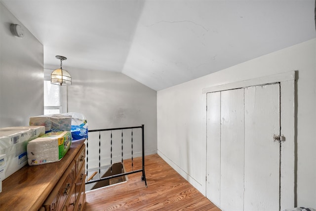 hallway with vaulted ceiling and wood finished floors