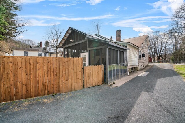 view of home's exterior with a gate, fence, a sunroom, and a chimney