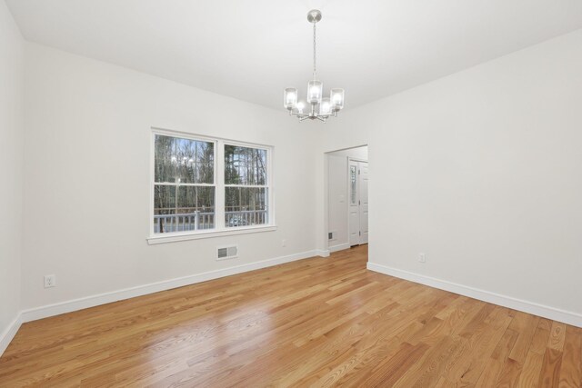 spare room with baseboards, visible vents, an inviting chandelier, and light wood finished floors